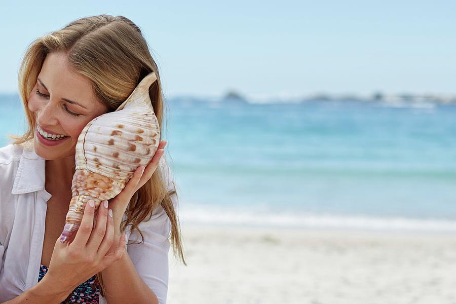 woman-listening-to-a-seashell-science-photo-library